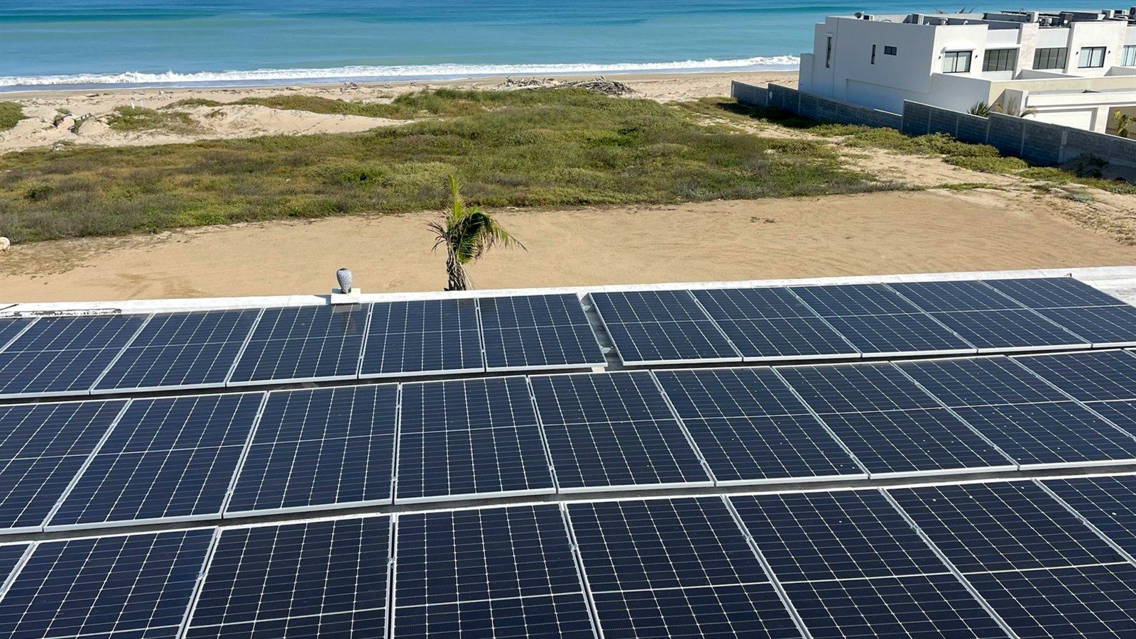 Paneles solares en azotea de una casa frente a la playa, instalados por Ecolux